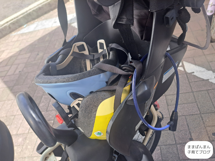 子ども乗せ自転車に子どものヘルメットを置いて鍵をかけている写真。