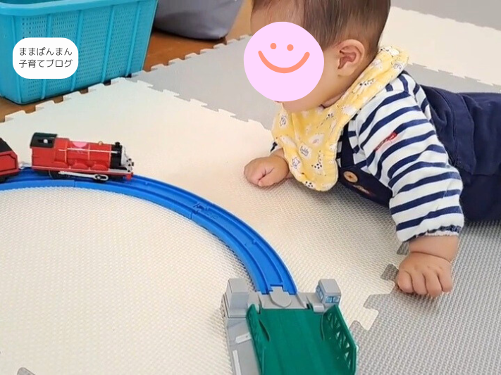 腹ばいしながらプラレールを見つめる赤ちゃん