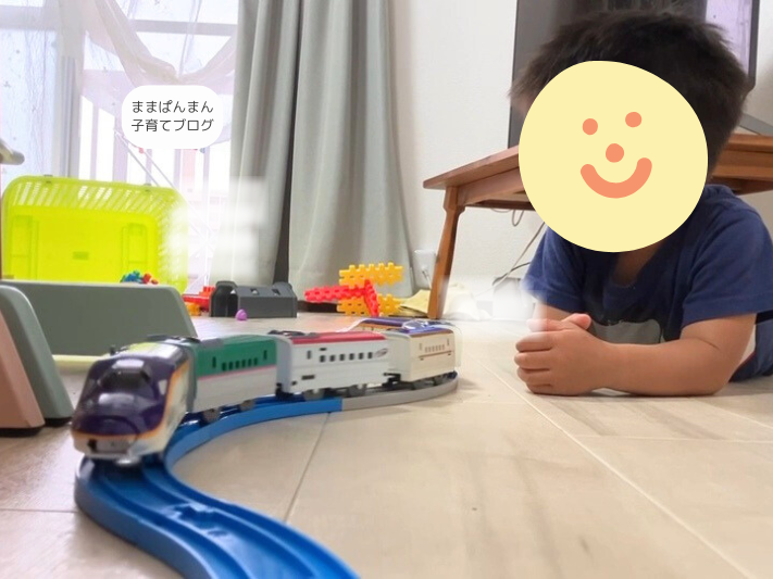 走っているプラレールを見つめる子ども